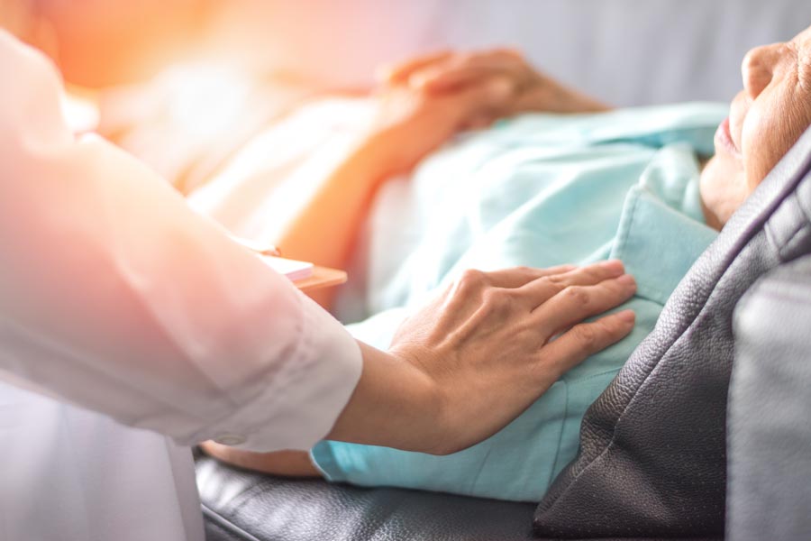 An end-of-life doula comforts a patient lying down