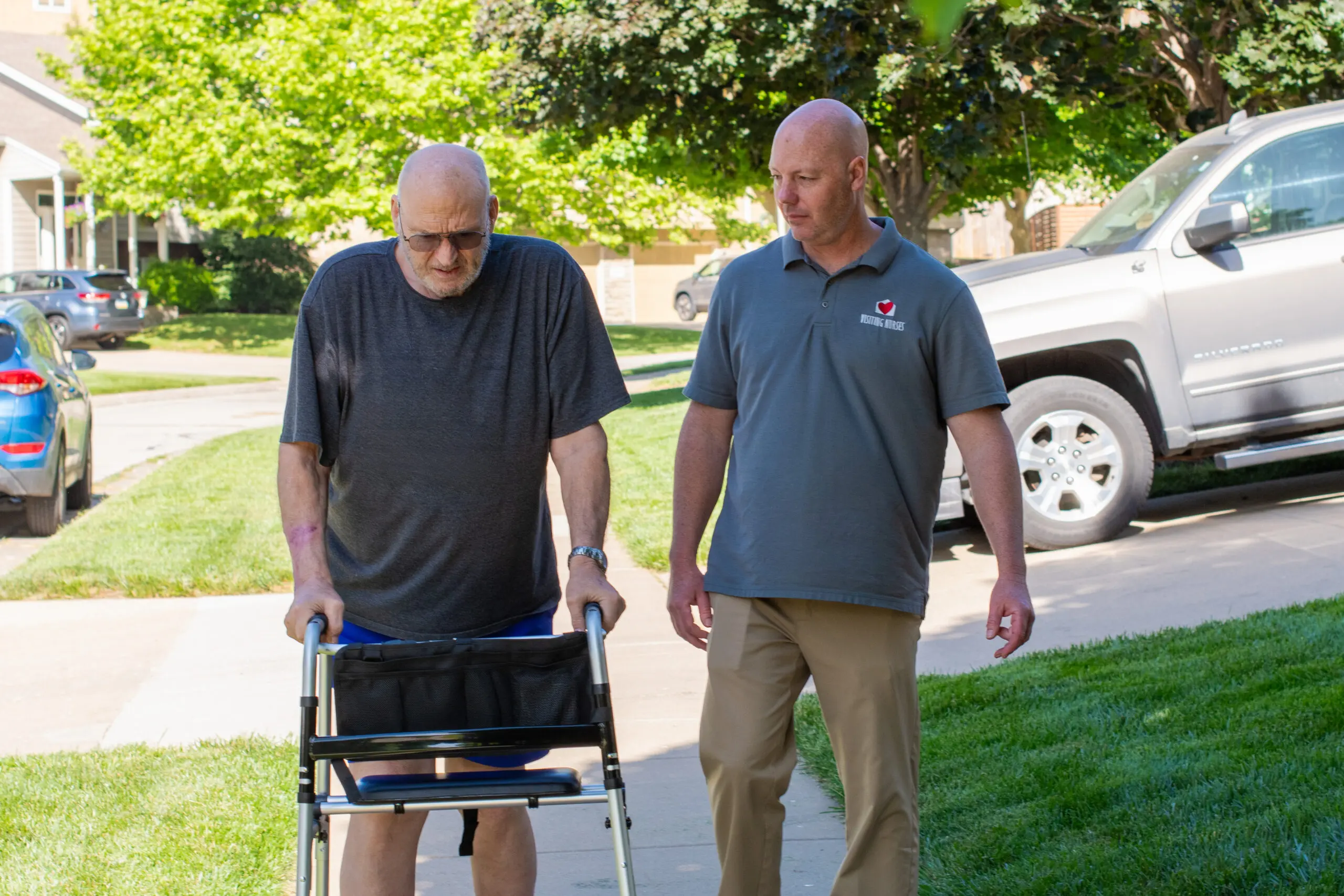 A VNA PTA walks with a patient in front of his home. 