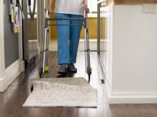 Person walking with walker approaches bunched rug.