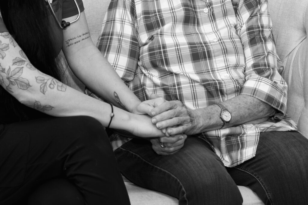 Hospice nurse holding a patient's hand. 